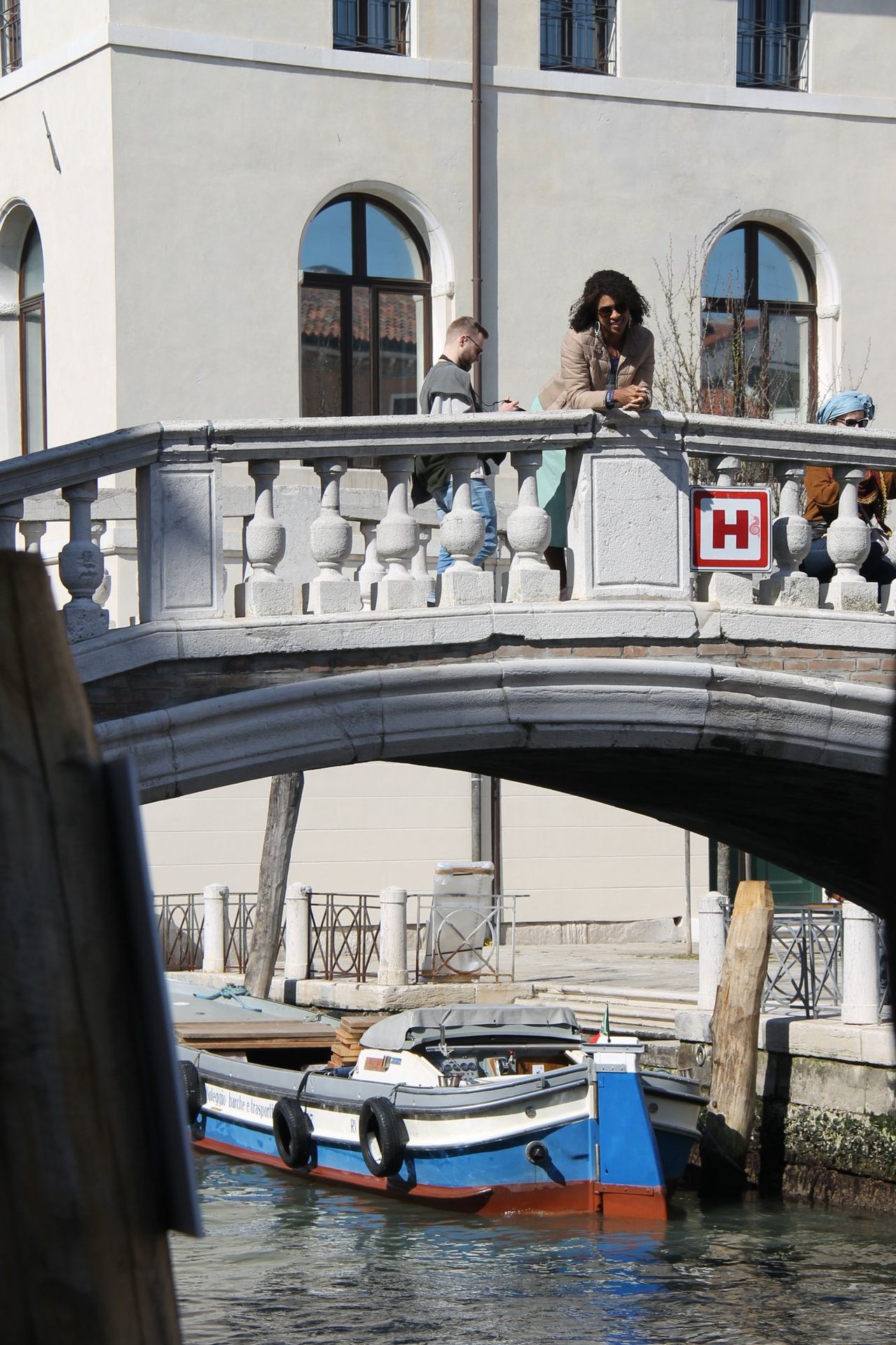 Viajante atravessando uma ponte de pedra branca sobre um canal de Veneza