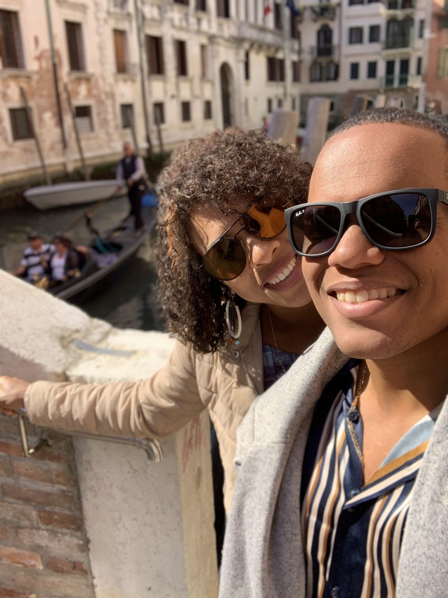 Casal em selfie em ponte de Veneza, com gôndola passando ao fundo