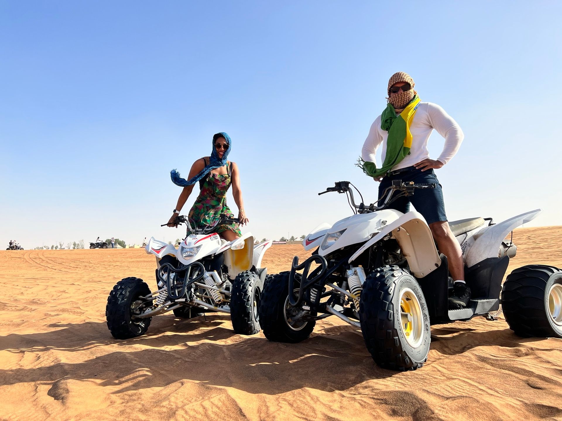 Casal de keffiyeh em quadriciclos no deserto de areia vermelha