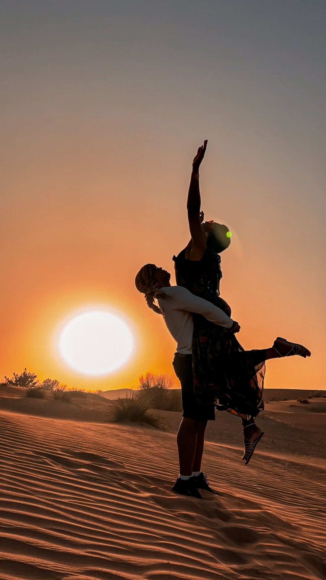 Silhueta do casal nas dunas do deserto ao pôr do sol