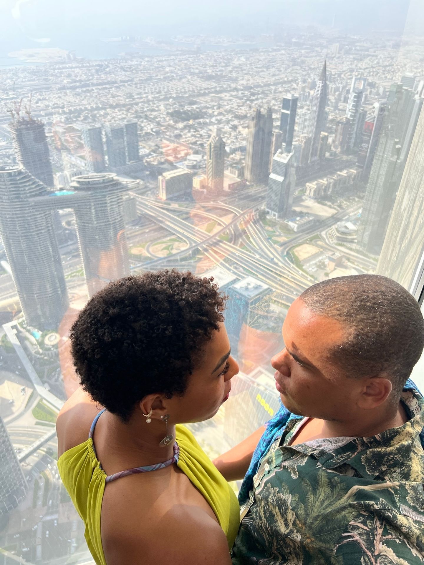 Casal no vidro do mirante do Burj Khalifa com a cidade abaixo