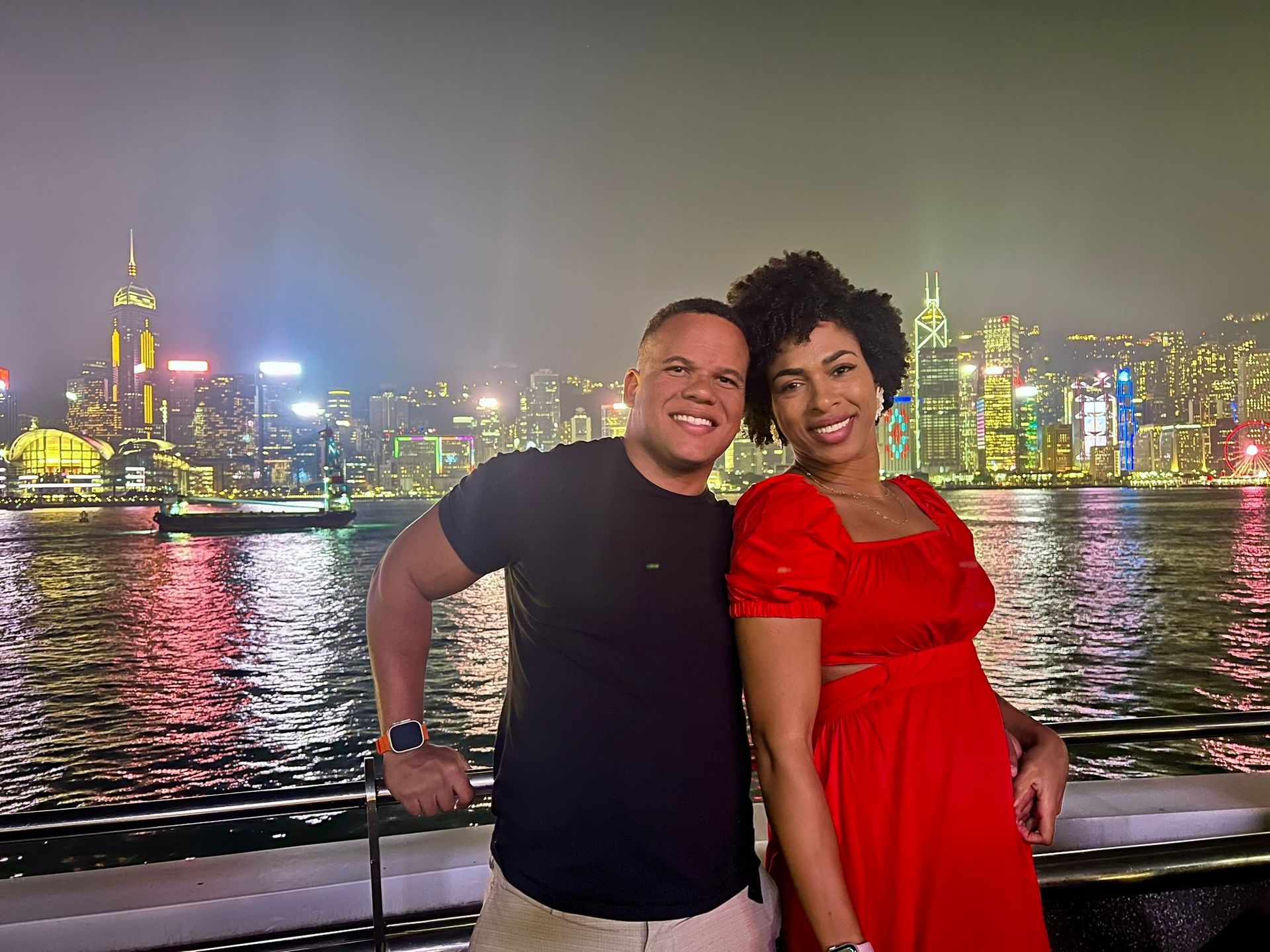 Casal na Avenida das Estrelas com o skyline noturno de Hong Kong ao fundo