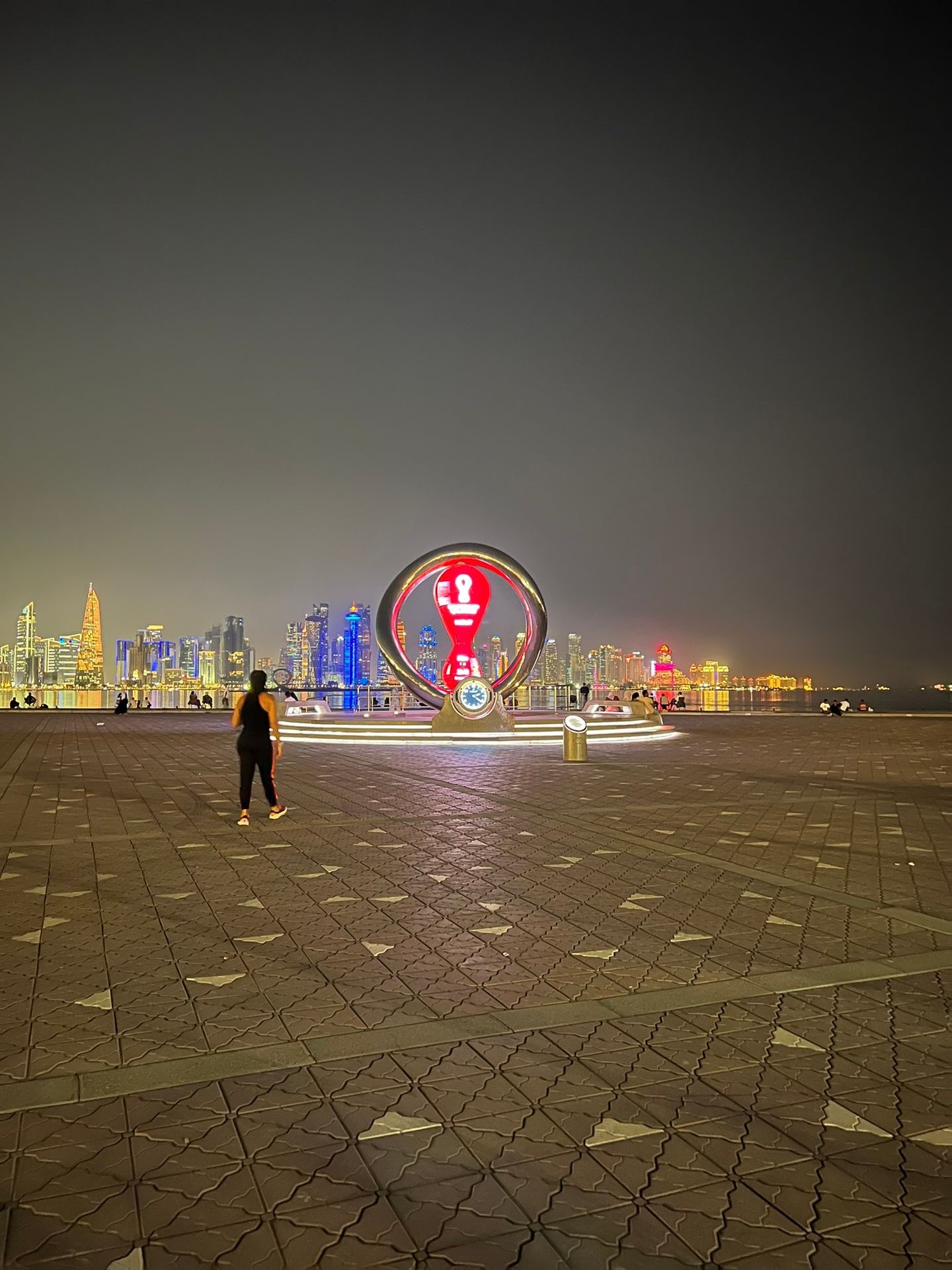 Calçadão da Corniche de Doha à noite com o skyline de West Bay ao fundo