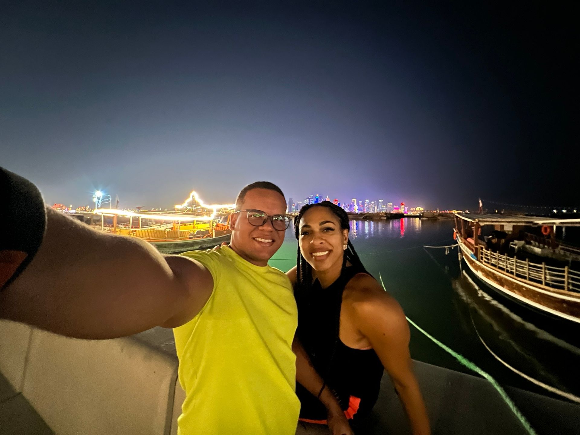 Casal na Corniche de Doha com dhows e o skyline ao fundo